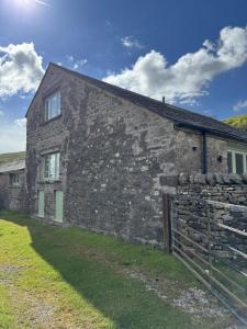 an old stone house with a fence in front of it at The Sheep Barn in Weathercote