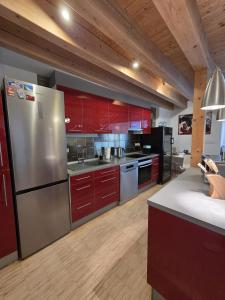 a kitchen with red cabinets and a stainless steel refrigerator at Apartmán Kräm in Klatovy