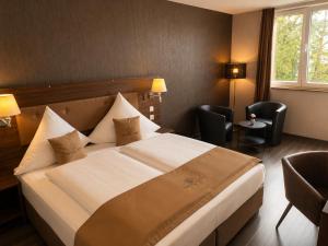 a hotel room with a large bed and two chairs at Hotel Pasa Paradies KOSTENLOSE PARKPLÄTZE in Hanau am Main