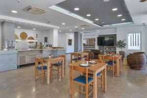 a kitchen and dining room with wooden tables and chairs at Naiades Hotel by Estia in Kato Gouves