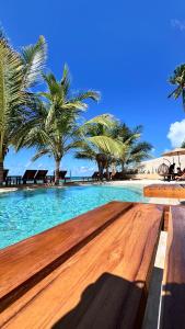 a wooden bench next to a swimming pool with palm trees at Tangawizi Lodge Zanzibar - Adults Only in Jambiani