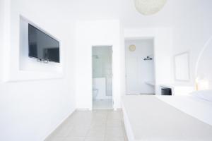 a white bedroom with a flat screen tv on a wall at Harmony Hotel in Sarandë