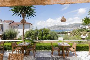 a patio with tables and chairs and a view of the ocean at Harmony Hotel in Sarandë