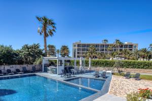 a pool with chairs and a hotel in the background at Naiades Hotel by Estia in Kato Gouves