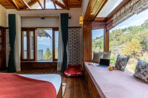 a bedroom with a bed with a laptop on it at SaffronStays Brookside Estate in Rānīkhet