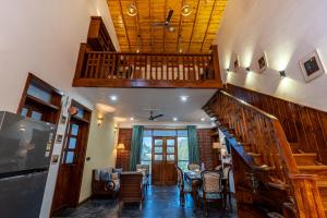 a living room with a staircase and a table and chairs at SaffronStays Brookside Estate in Rānīkhet