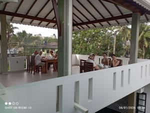 a group of people sitting at a table on a patio at The Ritz Hikkaduwa in Hikkaduwa