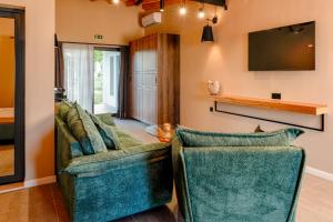 a living room with two green chairs and a tv at Maria village resort in Pavel Banya