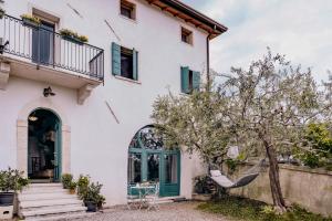 a white house with a green door and a tree at Corte Lavarini The Magic At Sight in Fumane