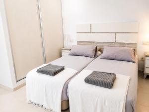 two beds in a room with white and purple at La Perla Blanca in Benijófar