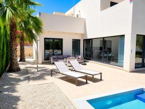 a villa with a swimming pool and palm trees at La Perla Blanca in Benijófar