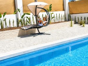 a woman sitting in a chair next to a swimming pool at La Perla Blanca in Benijófar +14 photos