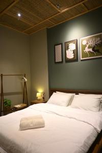 a bedroom with a large white bed with three pictures on the wall at Mer Home in Tây Ninh