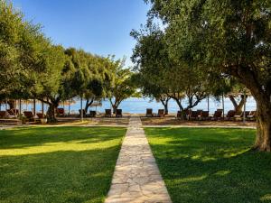 a path through a park with trees and benches at Belle Helene Hotel by GHH in Vathi