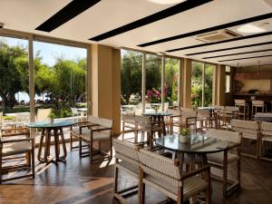 a restaurant with tables and chairs and large windows at Belle Helene Hotel by GHH in Vathi