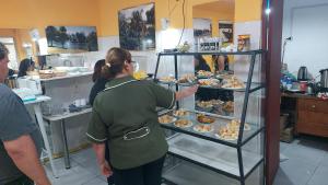 a woman pointing at a display case of pastries at Hotel Internacional in Tacuarembó