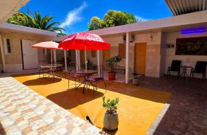 a patio with tables and chairs and a red umbrella at Hotel Internacional in Tacuarembó