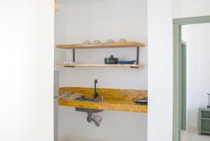 a kitchen with a sink and a shelf on the wall at Sand House in Imsouane