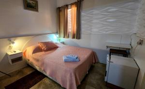 a small bedroom with a bed with a pink blanket at Hotel Internacional in Tacuarembó