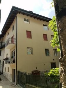 a white building with red windows and a black fence at B&B GabriEle in Molina di Ledro