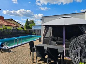 a table and chairs under an umbrella next to a pool at Villa Aqua Wągrowiec Pool House in Wągrowiec