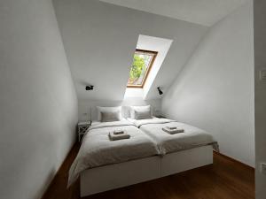 a white bedroom with a bed with a window at Barn House in Ptuj