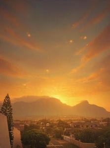 a sunset over a city with mountains in the background at T&A Escape in Grassy Park