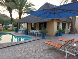 a house with a pool and chairs and an umbrella at Capbon Guesthouse in Windhoek