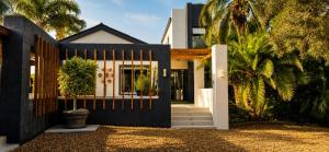 a house with a black gate and palm trees at Alimandi Villa in Klapmuts