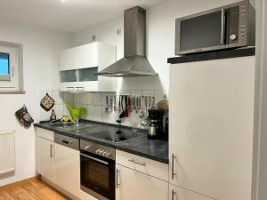 a kitchen with white cabinets and a microwave and a refrigerator at Komfortable Ferienwohnung mit Terrasse auf Fehmarn in Fehmarn