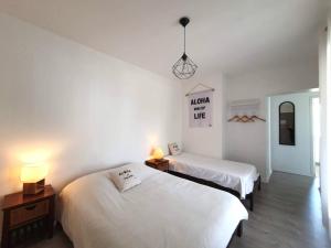 two beds in a room with white walls at Hôtel La Cote d'Argent in Seignosse