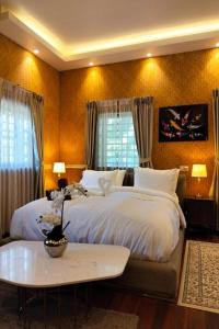 a bedroom with a large white bed and a table at Varaya Resort in Ban Kraek