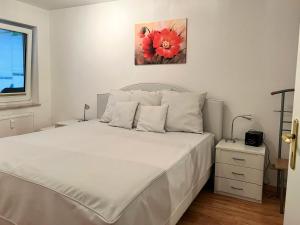 a bedroom with a white bed with a red flower painting on the wall at Komfortable Ferienwohnung mit Terrasse auf Fehmarn in Fehmarn