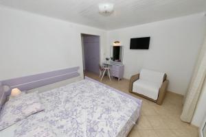 a bedroom with a bed and a chair and a television at Ribičić Guesthouse in Brela