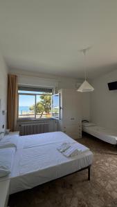 a white bedroom with a large bed and a window at hotel cri cri - fronte spiaggia in Silvi Marina