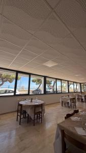 a dining room with tables and chairs and windows at hotel cri cri - fronte spiaggia in Silvi Marina +11 photos