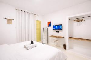 a bedroom with a white bed and a tv at Elia's House renovated in Canggu