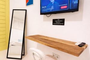 a tv on a wall with a mirror and a sink at Elia's House renovated in Canggu +16 photos