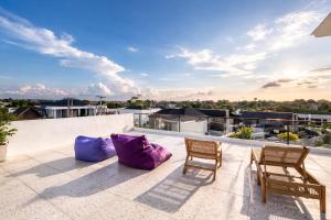 a patio with two chairs and purple pillows on a roof at Elia's House renovated in Canggu
