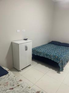 a bedroom with a bed and a dresser with a bedskirts at Casa aconchegante centro in Peruíbe