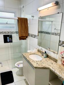 a bathroom with a sink and a mirror and a toilet at Casa aconchegante centro in Peruíbe