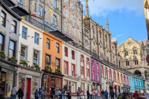 a group of buildings on a street with people walking around at MEININGER Hotel Edinburgh Haymarket in Edinburgh