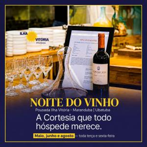 a advertisement for a wine bottle and glasses on a table at Pousada Ilha Vitoria in Ubatuba