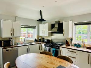 a kitchen with white cabinets and a wooden table at The Priory Cottage in Legbourne