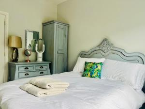 a white bed with towels on it with a dresser at The Priory Cottage in Legbourne