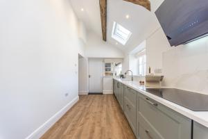a kitchen with white cabinets and a skylight at Stretton Lower hall in Malpas