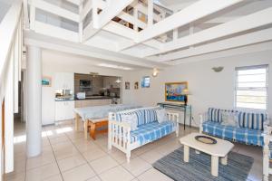 a living room with blue and white furniture and a kitchen at Seabreeze Bungalow in Langebaan +22 photos