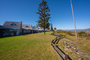 a wooden fence next to a tree and a house at Seabreeze Bungalow in Langebaan