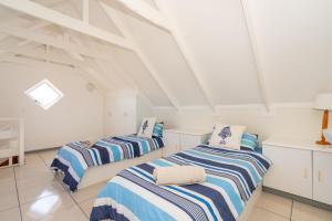 two beds in a room with white walls at Seabreeze Bungalow in Langebaan