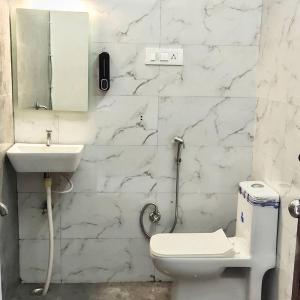 a white bathroom with a toilet and a sink at The Udaikot farm in Rāma